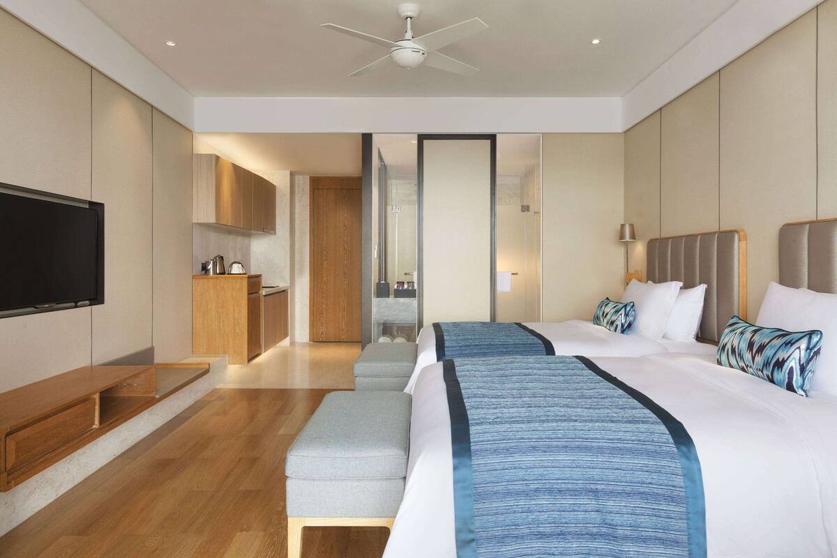 Une chambre d’hôtel dotée d’un grand lit, d’une télévision, d’une kitchenette et d’une salle de bain visible à travers une porte en verre.