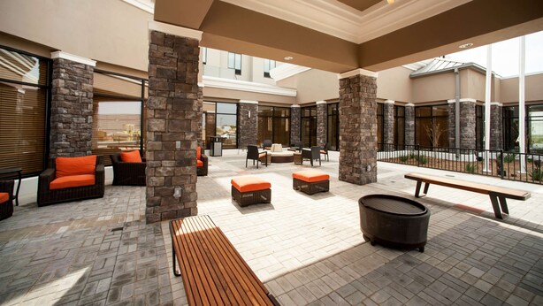 Un patio al aire libre con pilares de piedra, asientos y un banco de madera.