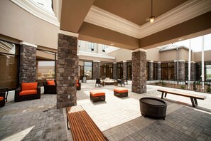 Un espace extérieur aménagé en patio, avec des piliers en pierre, des sièges et un banc en bois.