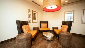 Una habitación con muebles de mimbre, cojines anaranjados y una lámpara roja grande.