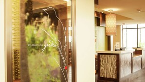Zona de recepción con un amplio ventanal que ofrece vistas a un jardín, un mostrador de recepción y una decoración de estilo moderno.