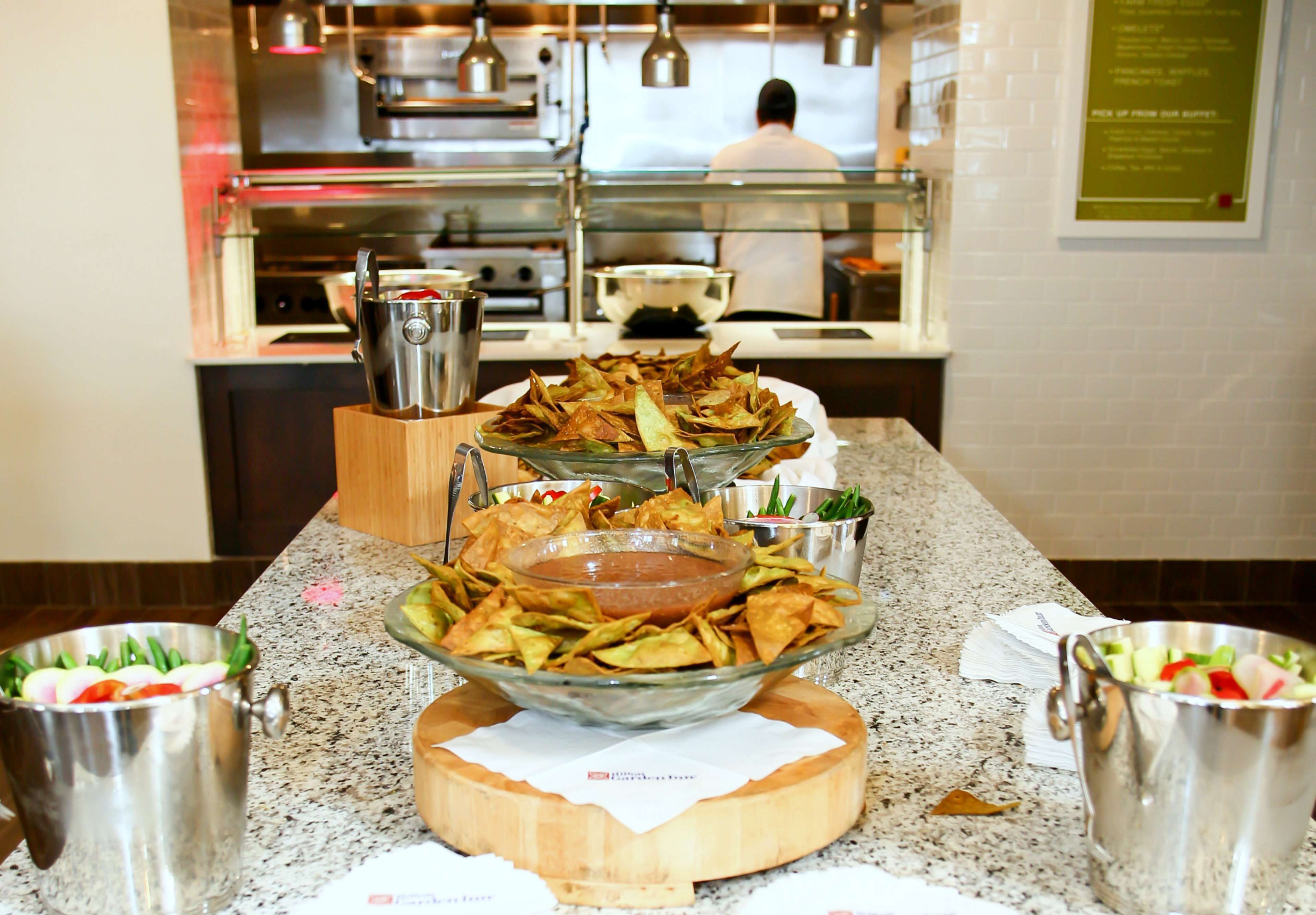 A buffet setup with various dishes and a chef in the background.