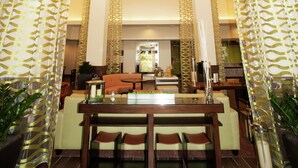 Un amplio vestíbulo con zona de comedor central, techos altos y luminarias modernas.