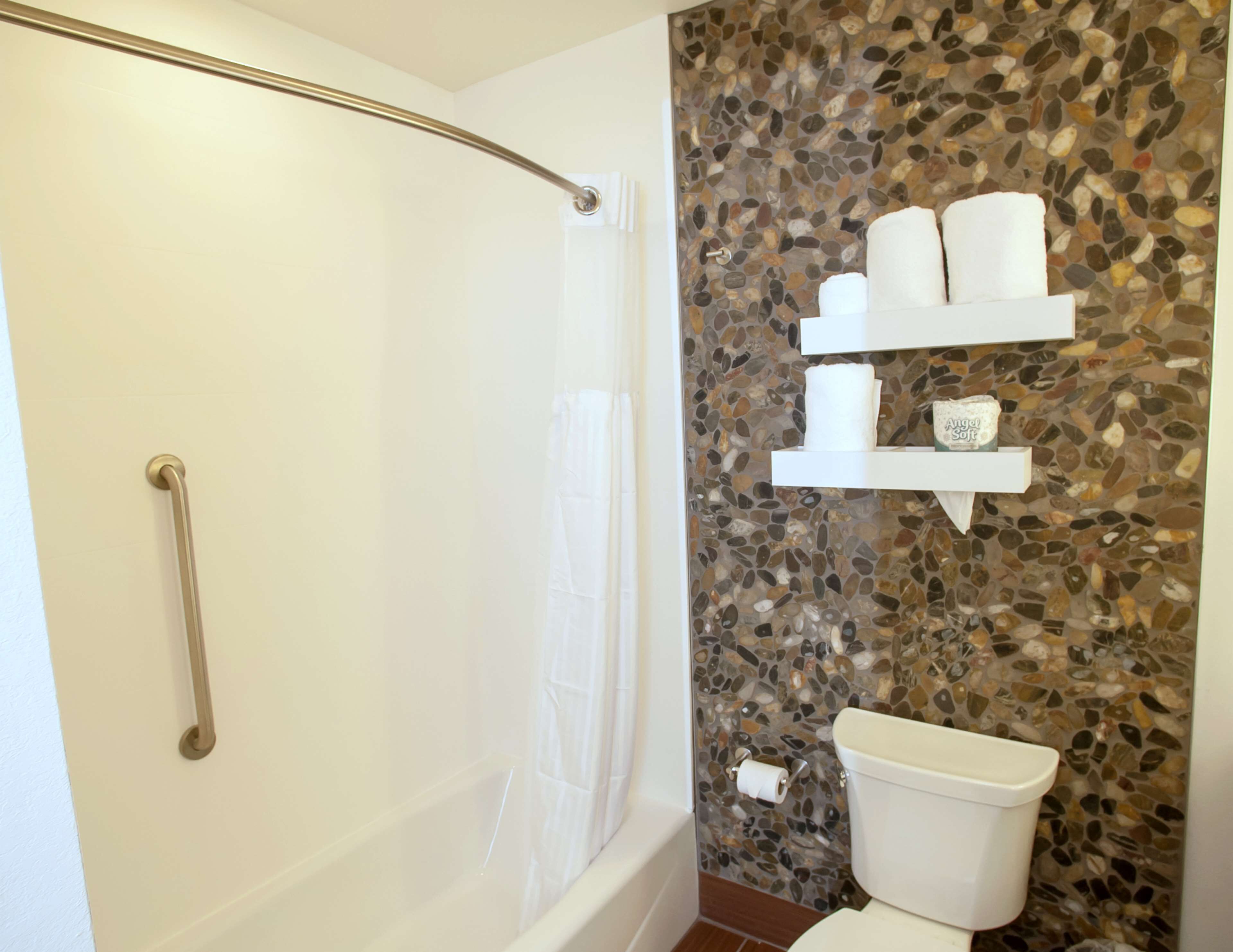 Une salle de bain avec douche, toilettes et un mur décoré de mosaïques.