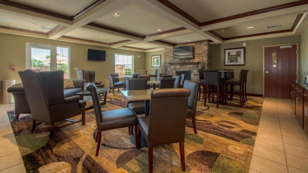 A spacious lobby with multiple seating areas, a fireplace, and a television mounted on the wall. - Creekstone Inn & Suites  (St. Marys)