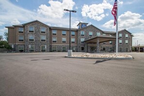 Ein mehrstöckiges Hotel mit einer steinernen Fassade, einem zentralen Eingang und einer amerikanischen Flagge.