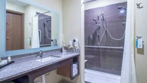 A bathroom with a sink, mirror, towel rack, and shower. - Creekstone Inn & Suites  (St. Marys)