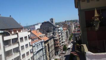 Un paisaje urbano con edificios de varios pisos, cielo despejado y una calle con vehículos.