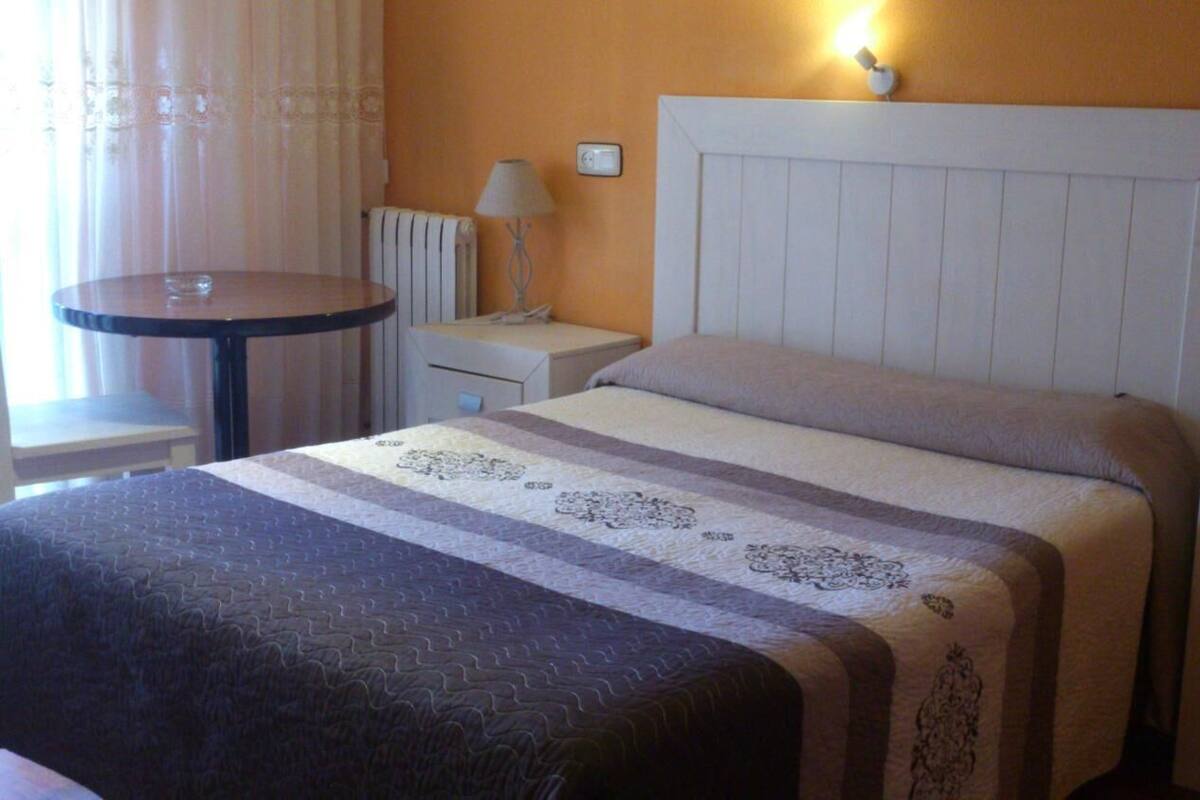 Une chambre d’hôtel comprenant un lit, une table de chevet, une lampe, une commode et un téléphone.