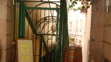 A restaurant entrance with a sign reading "Los Osos Restaurante," a green gate, a wooden barrel, and a menu board.