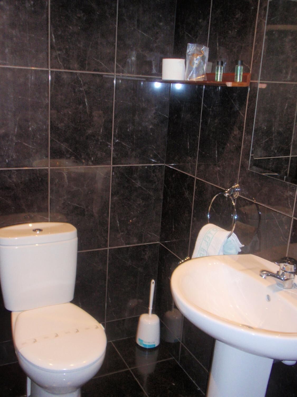 A bathroom with a toilet, sink, and a hand dryer.