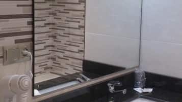 Un baño moderno con encimera negra, lavabo blanco, secador de pelo y toalla.