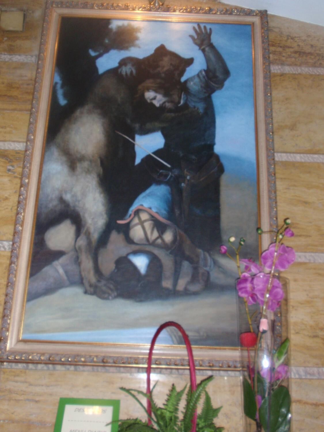 Un cuadro enmarco que muestra a un hombre y un perro con correa, con un jarrón de flores al frente.