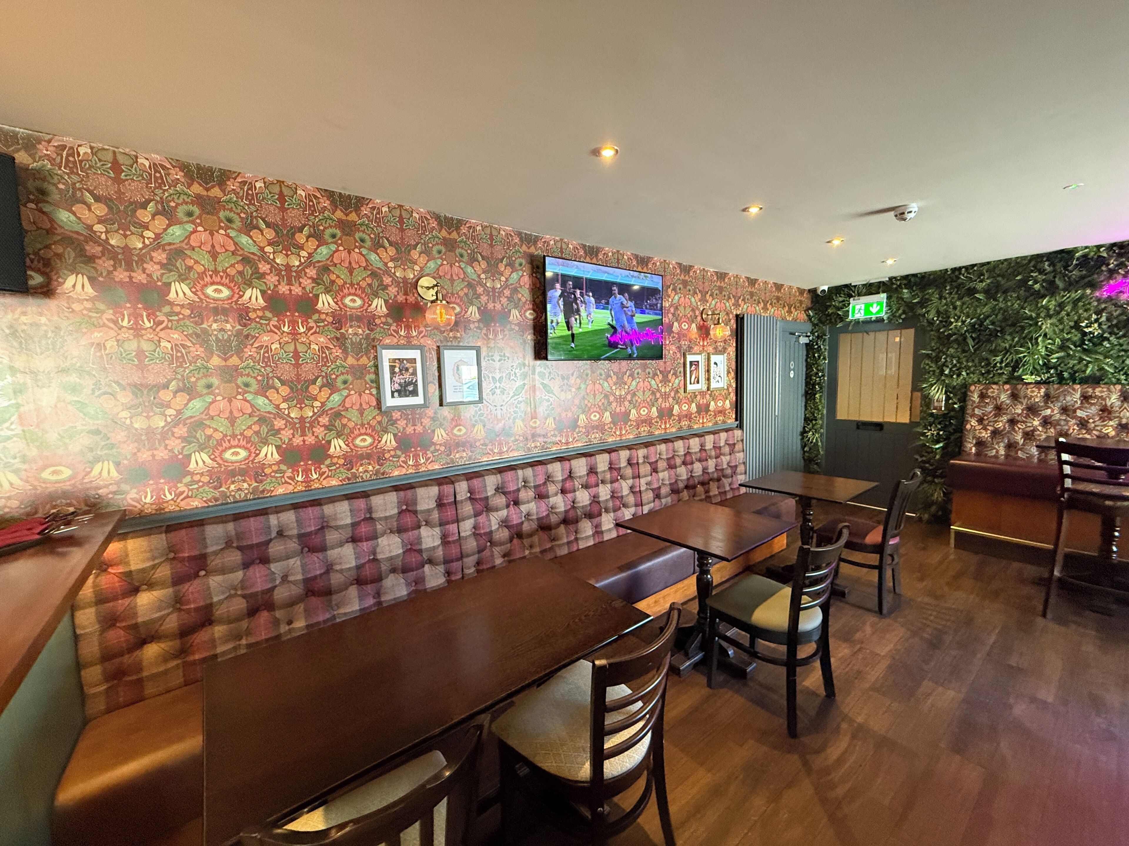 Un restaurant avec un mur décoré de motifs, des tables en bois et des banquettes rembourrées.