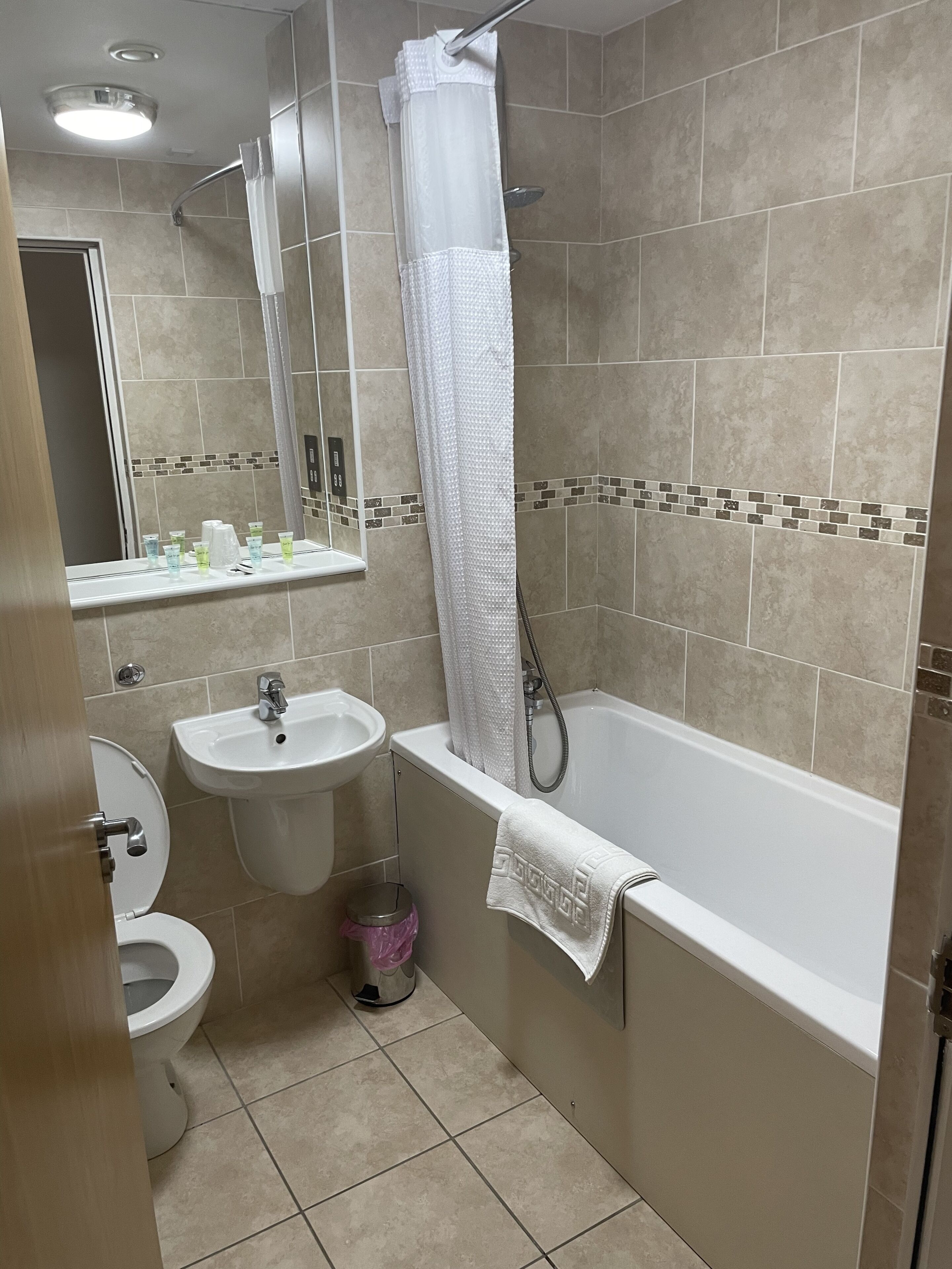Un baño con bañera, lavamanos, inodoro y espejo.