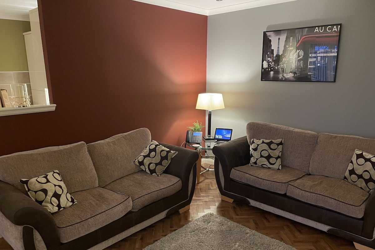 A living room with two sofas, a lamp, a small table, and a framed picture on the wall.