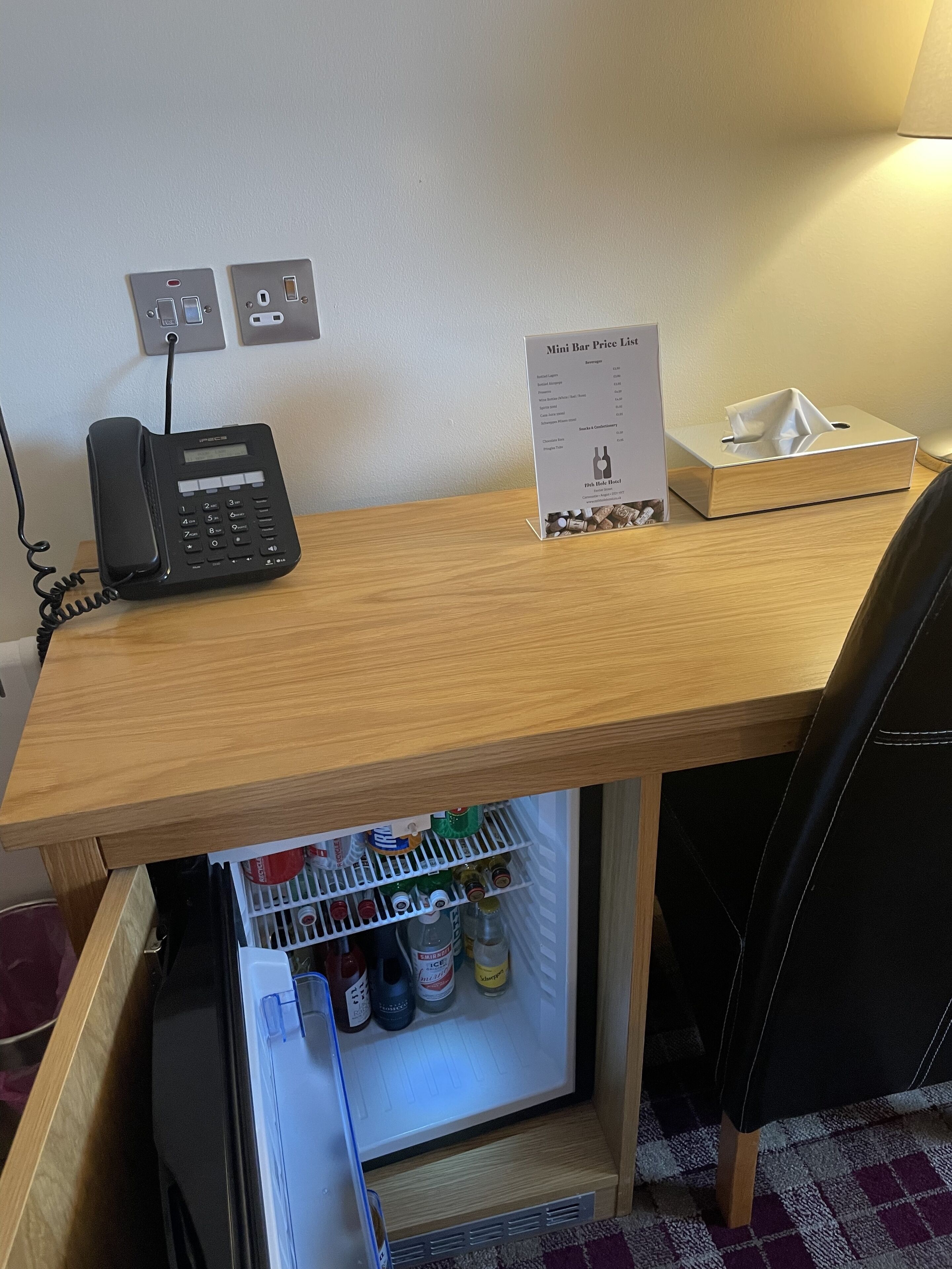 Una reception d'hotel con un telefono, un listino prezzi del minibar e un portaserviti.