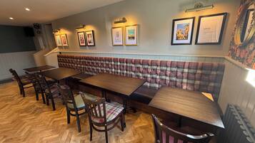 A dining area with a long wooden table, upholstered bench seating, and wooden chairs.