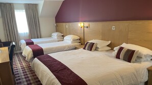 A hotel room with three beds, a wooden headboard, a checkered floor, and a window with curtains. - 19th Hole Hotel (Carnoustie)