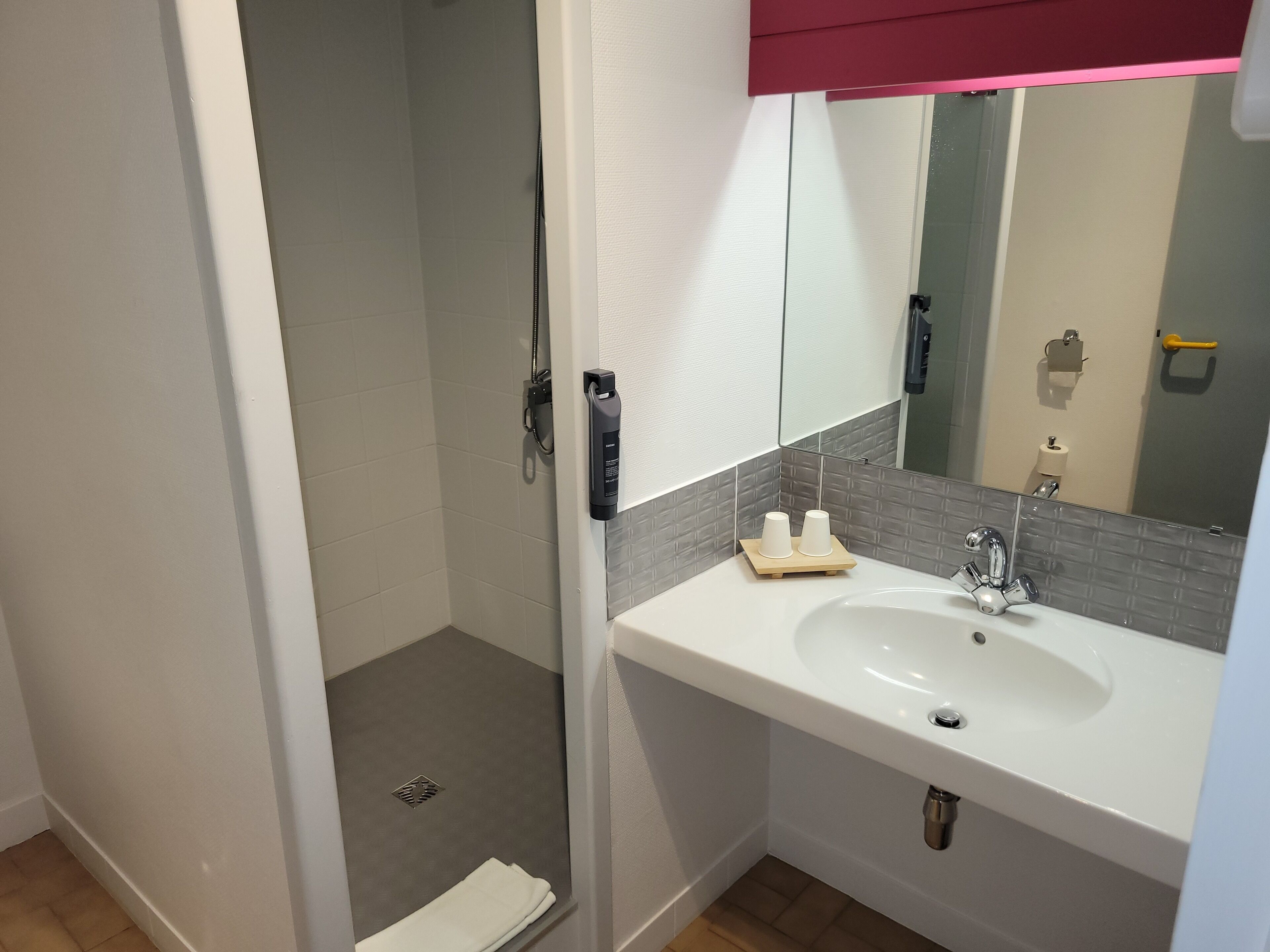 A bathroom with a white sink, a mirror, and a shower area.