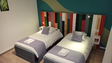 Ein Zimmer mit zwei Betten, jedes mit einem Kopfteil mit bunten Streifen.
