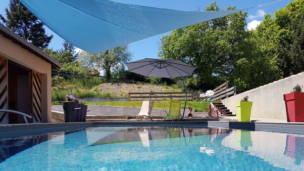 Una piscina con agua azul cristalina, rodeada por una terraza con sillas de descanso y una zona con sombra.