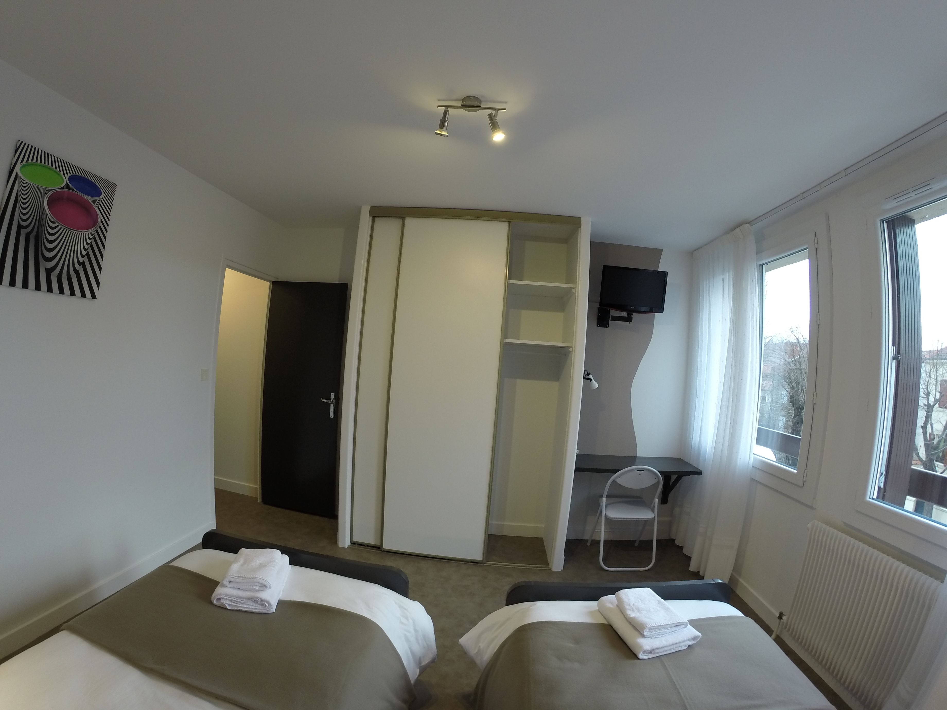 Une chambre d’hôtel avec deux lits, un bureau, une télévision et une fenêtre.