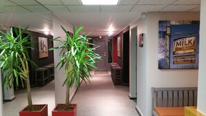 Un pasillo con plantas en macetas, un radiador y un cartel que dice 'Bebe leche'.