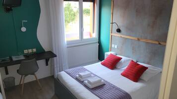Une chambre d’hôtel avec un lit, un bureau, une chaise, une télévision et une fenêtre avec des rideaux.