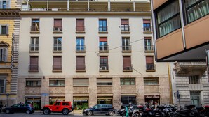 A multi-story building with balconies, a massage center, and parked cars. - Daplace - Hotel Gran Torino Suites (Rome)
