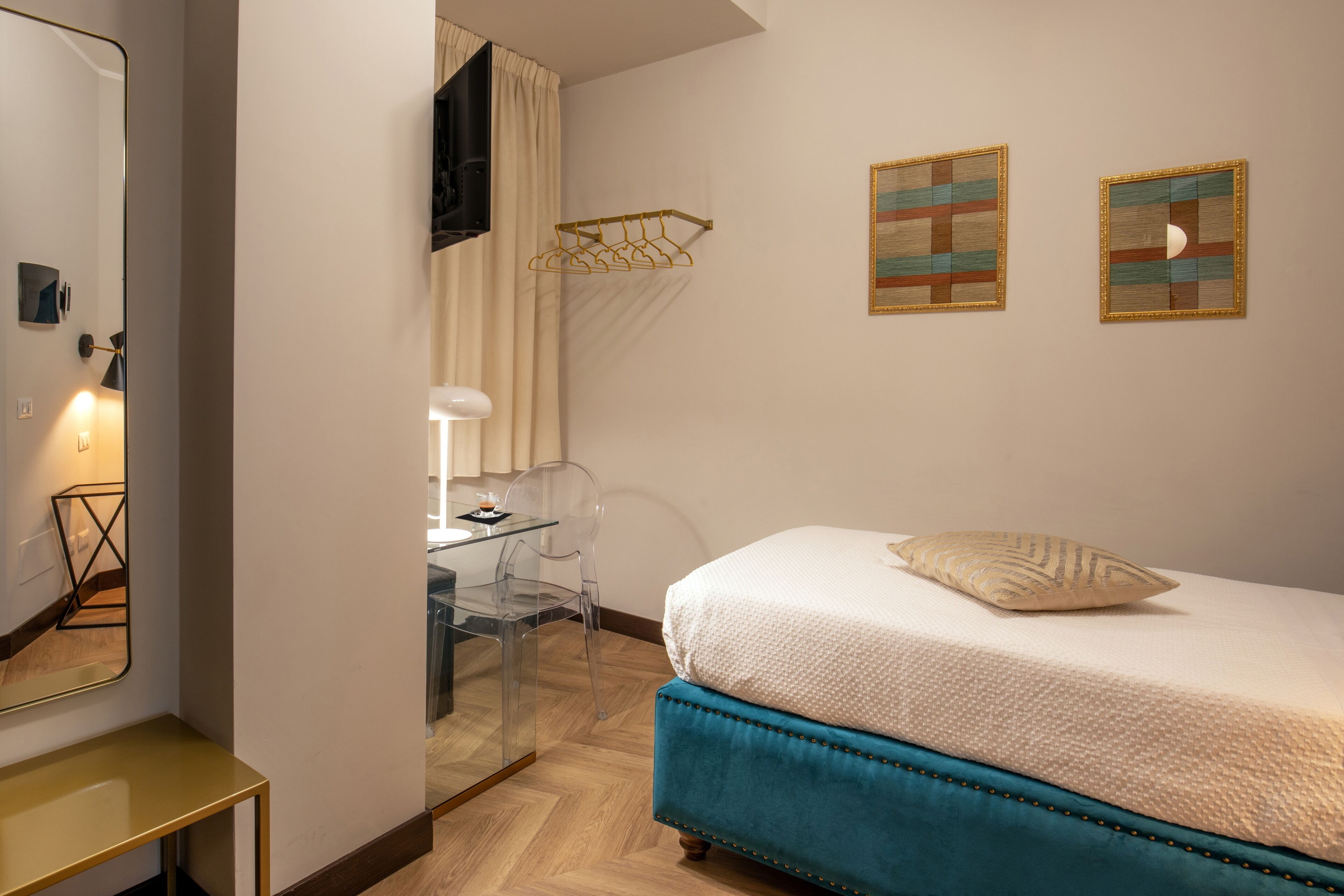 Ein Schlafzimmer mit einem Bett, einem Schreibtisch und einem Stuhl. Zwei Wandbilder und eine Hängeleuchte sind vorhanden.
