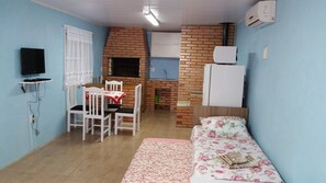 Um espaço compacto com área de jantar, kitchenette e cama.