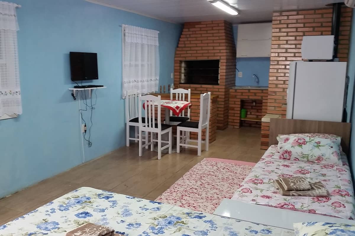 Un espacio habitable compacto con comedor, sofá y una pequeña cocina junto a una pared de ladrillo.