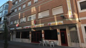 A multi-story building with a sign reading "HOSTAL" indicating it is a hostel. There are multiple windows on each floor, and the building has a brick facade. - Hostal Goyma I (San Fernando de Henares)