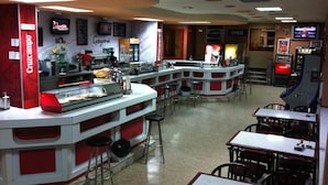 A restaurant with a counter, stools, and tables. - Hostal Goyma I (San Fernando de Henares)