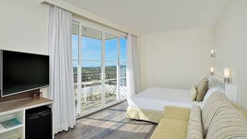 A hotel room with a bed, a TV, a small desk, and a balcony with a view.