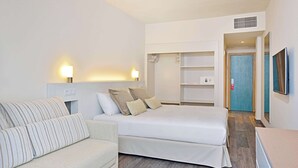 A hotel room with a bed, a sofa, a wardrobe, and a TV.