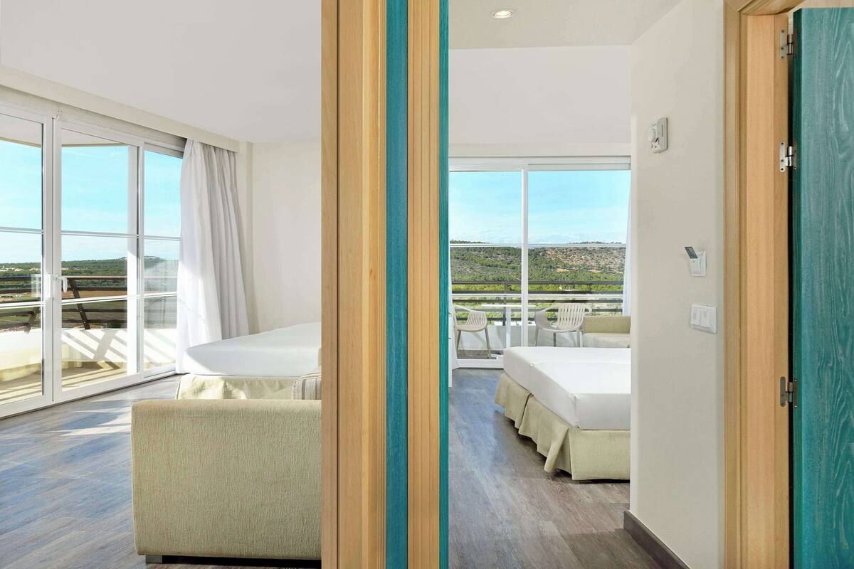 Een moderne hotelkamer met een grote schuifglazen deur naar een balkon met een prachtig uitzicht.