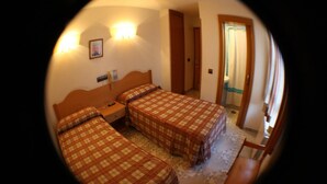 Habitación con tres camas, cada una con colcha a cuadros, cabecero de madera y mesita de noche con teléfono.