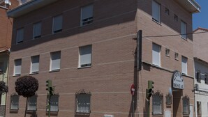 Un edificio de varios pisos con fachada de ladrillo, múltiples ventanas con contraventanas y un cartel que indica una oficina de correos.