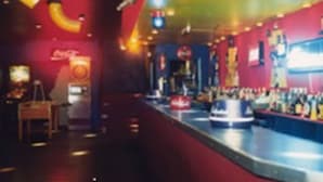 Un bar con mostrador, letreros de neón y el logotipo de Coca-Cola.