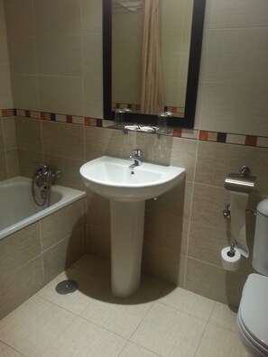 A bathroom with a sink, bathtub, toilet, and a mirror.