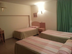 A room with two single beds, a small desk, and a chair.