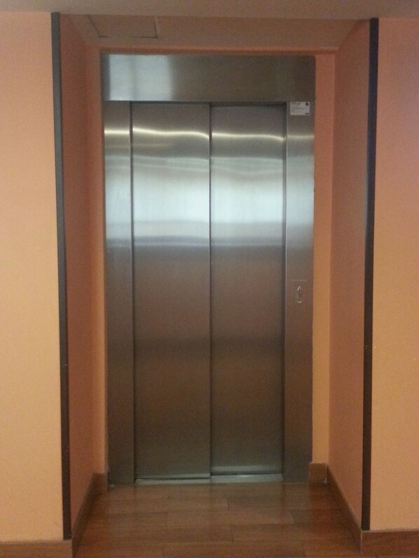 Un ascensor moderno con detalles metálicos y un panel de control a la derecha.