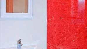 Un baño con un lavamanos blanco y una pared con azulejos rojos.