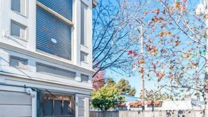 A residential building with a garage door, a brick patio, and a wooden fence. - Bright & Spacious One Bedroom Apartment (Oakland)
