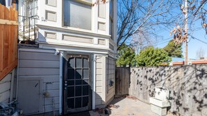 A garage with a large door, a wooden fence, and a tree in the background. - Bright & Spacious One Bedroom Apartment (Oakland)
