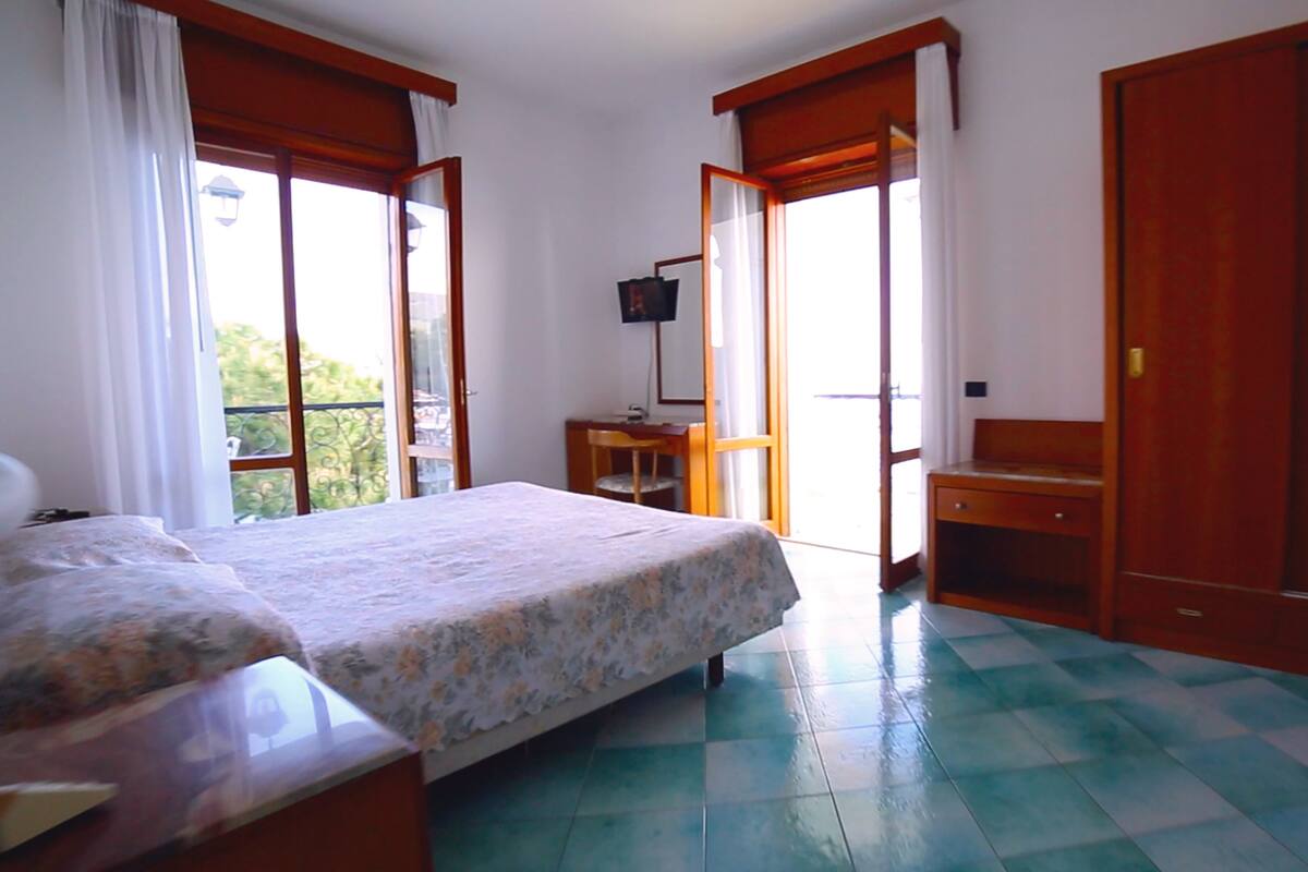 A bedroom with a bed, a desk, and a wardrobe.