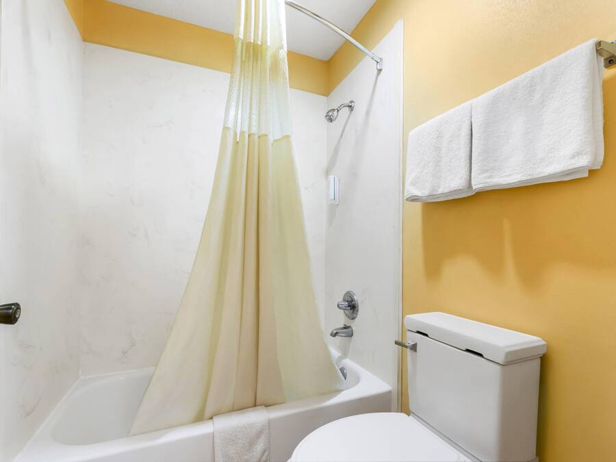 Un baño con bañera, inodoro y cortina de ducha.