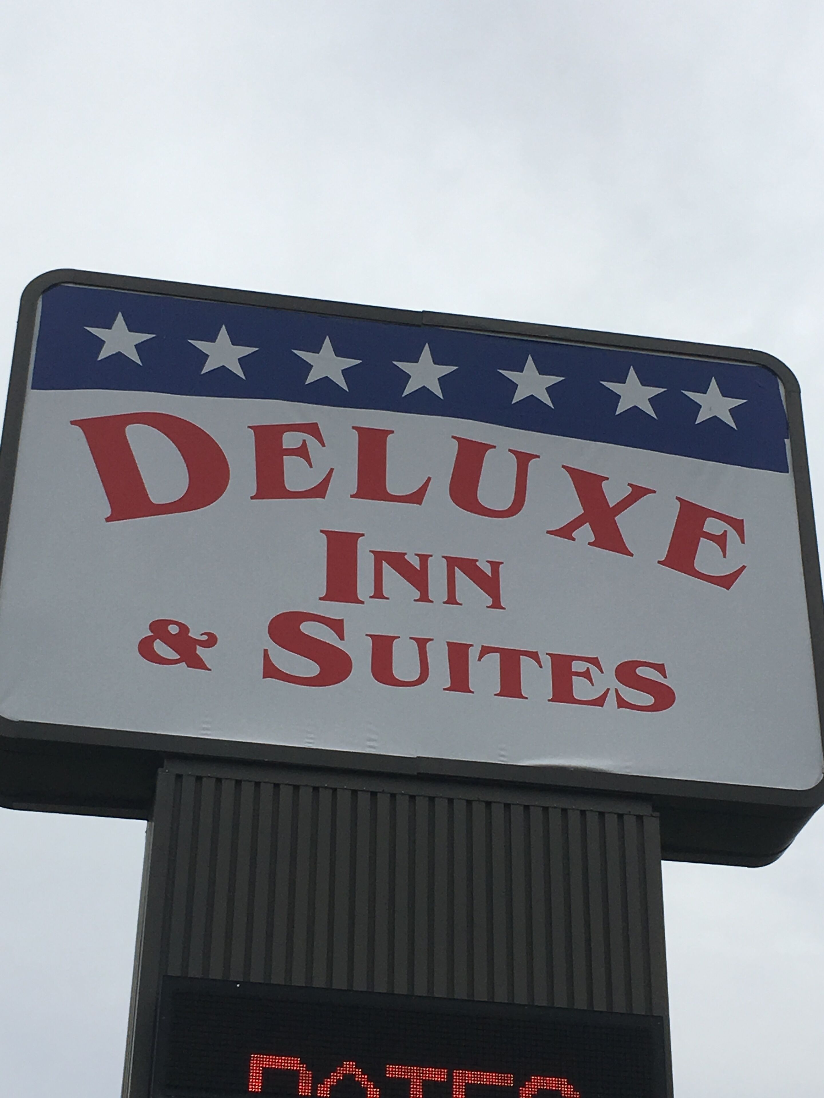 A sign for DELUXE INN & SUITES with a digital display below it.